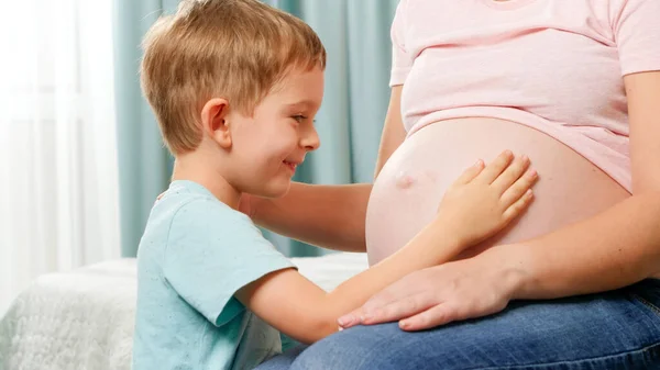 Feliz niño sonriente tocando el vientre grande de su madre embarazada esperando al bebé — Foto de Stock