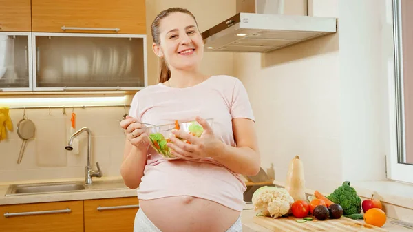 Feliz sorrindo mulher grávida com barriga grande segurando tigela grande com salada de legumes frescos — Fotografia de Stock