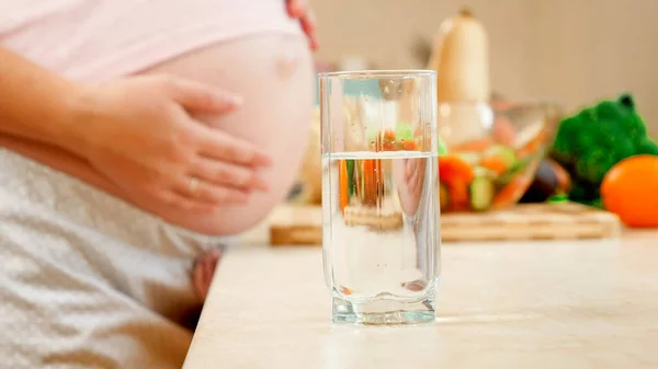 彼女の大きな腹と飲料水に触れる妊婦の笑顔の肖像画。妊娠中の健康的なライフスタイル、栄養と水分補給の概念 — ストック写真