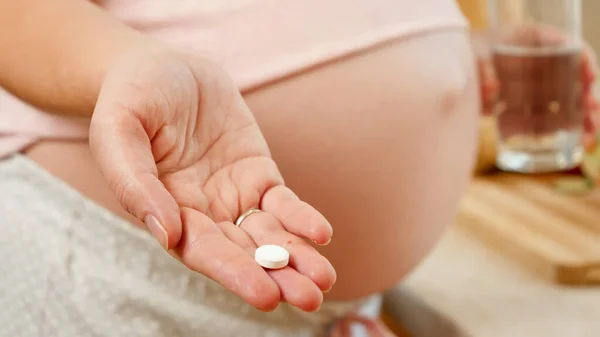 Egy fiatal nő közelsége, aki orvosi tablettát vagy vitamint vár a babától. Az egészséges életmód, táplálkozás és hidratáció koncepciója a terhesség alatt — Stock Fotó