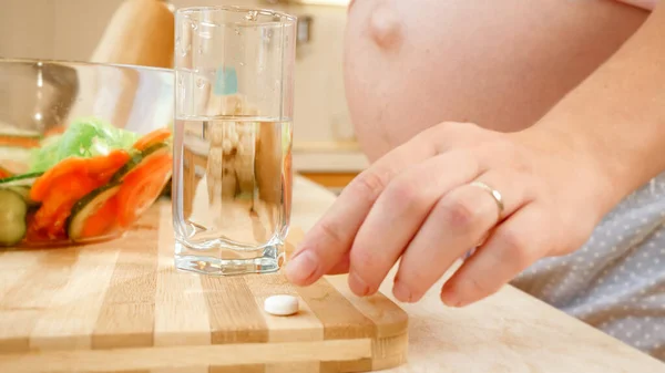아침 식사를 하기 전에 비타민 알약을 먹고 맑은 물을 마시는 임신부의 모습이 눈에 띈다. 건강 한 생활 방식, 영양 섭취 및 임신중의 수분 공급의 개념 — 스톡 사진
