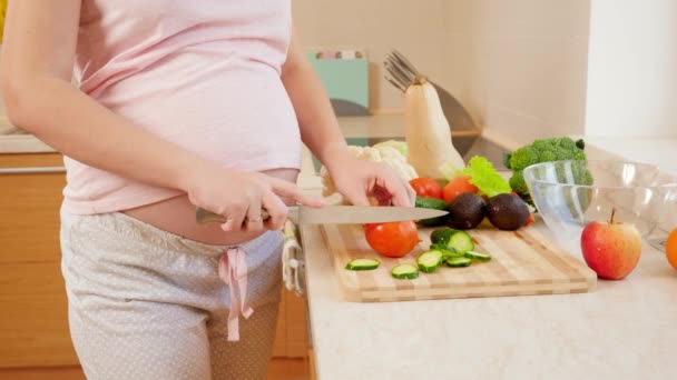 CPrimo piano di incinta yougn donna che cucina in cucina e taglio di pomodoro fresco. Concetto di stile di vita sano e nutrizione durante la gravidanza — Video Stock