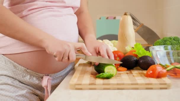 Доллі відео вагітної жінки, яка чекає на дитину, готуючи здоровий овочевий салат на кухні. Концепція здорового способу життя та харчування під час вагітності — стокове відео