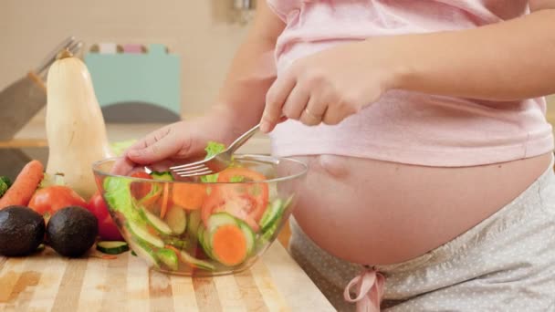 Primo piano di donna incinta che aspetta il bimbo che mangia l'insalata fresca saporita da boccia di vetro grande su cucina. Concetto di stile di vita sano e nutrizione durante la gravidanza — Video Stock