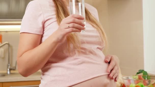 Retrato de una hermosa mujer embarazada con el vientre grande esperando a que el vientre beba agua dulce y sonriendo. Concepto de estilo de vida saludable, nutrición e hidratación durante el embarazo — Vídeo de stock