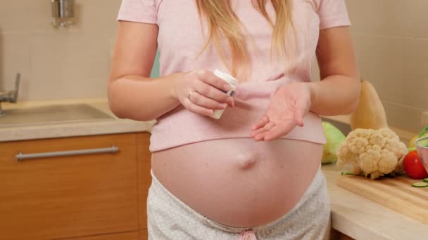 Egy terhes nő, akinek nagy hasa van, orvosi tablettákat és gyógyszereket tart a kezében. Az egészséges életmód és táplálkozás koncepciója a terhesség alatt — Stock videók