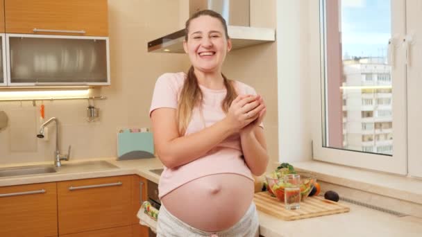 Heureuse femme enceinte souriante qui s'amuse avec pomme mûre rouge sur la cuisine le matin. Concept de mode de vie sain, nutrition et hydratation pendant la grossesse — Video