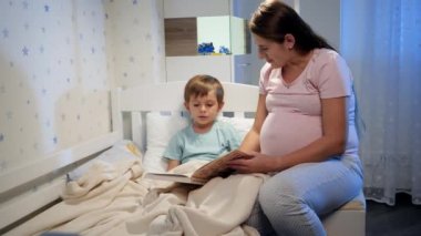 Güzel hamile anne, uyumadan önce büyük oğluna masal kitabı okurdu. Ebeveynler çocuklara kitap okuyor