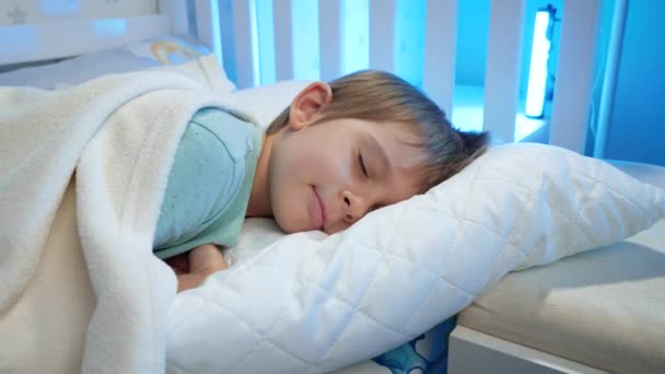 一个可爱的蹒跚学步的男孩躺在床上，晚上睡觉的画像。让美丽的孩子在床上安静下来 — 图库视频影像