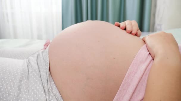 Gros plan de la femme enceinte caressant et touchant son bébé à naître se déplaçant et battant dans le gros ventre. Concept de grossesse, préparation et attente de l'enfant — Video