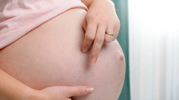 Närbild av finger wlalking på stor mage gravid kvinna står hemma. Begreppet förväntan och väntar på barnet — Stockfoto