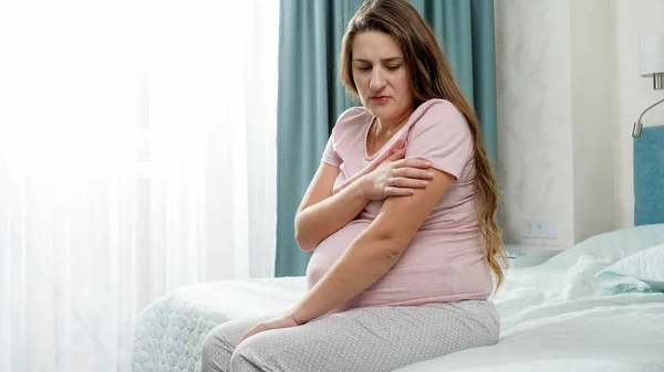 Sorgsen gravid kvinna sitter och skakar på sängen. Begreppet moderns och graviditetens depression. — Stockfoto