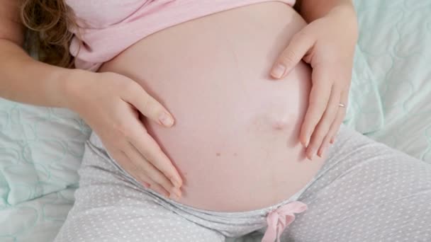 Närbild av gravida kvinnor händer gör hjärtat form på stor mage. Begreppet förväntar barn, kärlek och föräldraskap. — Stockvideo