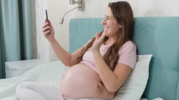 Retrato de mujer embarazada sonriente feliz teniendo video charla o conferencia en teléfono inteligente. — Vídeo de stock