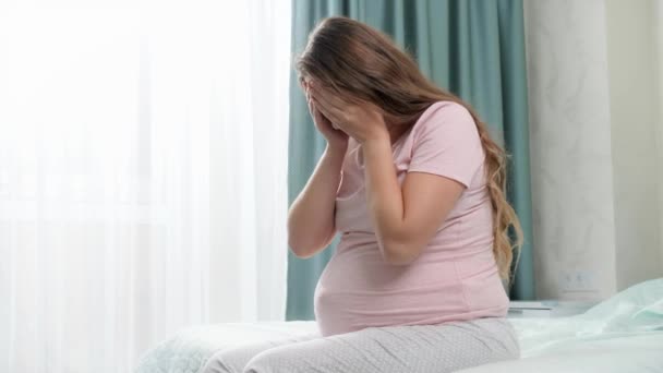 Jeune femme enceinte souffrant de dépression pleurant sur le lit. Concept de dépression maternelle et de grossesse. — Video