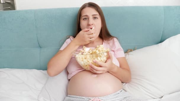 Retrato de una mujer divertida sintiendo hambre comiendo palomitas de maíz y agarrándolo con la mano de un tazón grande. Concepto de bulimia y comer en exceso — Vídeos de Stock