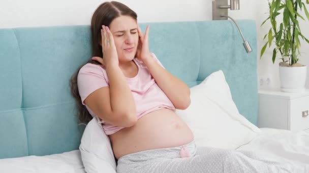 Yatakta baş ağrısından muzdarip hamile bir kadının portresi. Hamilelik süresince sağlık ve acı kavramı — Stok video