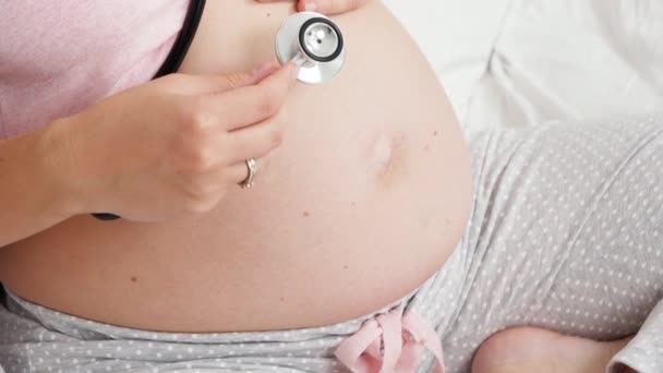 Nauwe arts die stethoscoop gebruikt tijdens het luisteren naar zijn zwangere vrouwelijke patiënt. Concept van gezondheidszorg en medisch onderzoek tijdens de zwangerschap. — Stockvideo