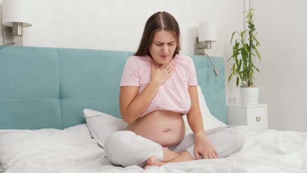 Eine junge schwangere Frau wacht morgens auf und fühlt sich unwohl und leidet unter Übelkeit. Vergiftung während der Schwangerschaft — Stockvideo