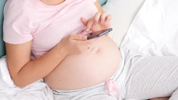 Top view felvétel fiatal terhes nő nagy hasú böngészés internet és okostelefon használata — Stock videók