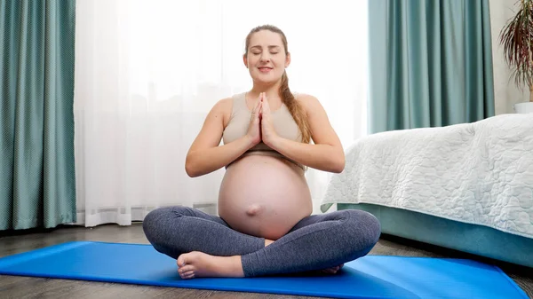 Portret van een prachtige msiling zwangere vrouw mediteren en doen yoga. Concept van gezonde levensstijl, gezondheidszorg en sport tijdens de zwangerschap — Stockfoto