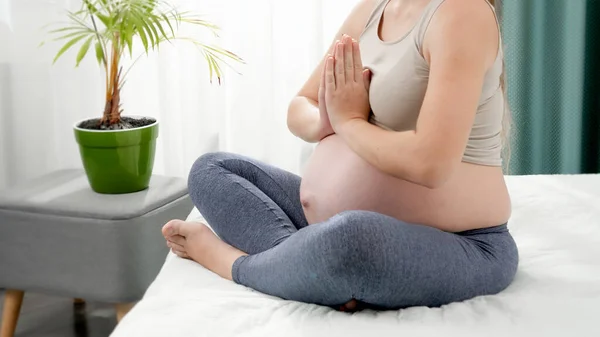 Lotus pozitinde oturup, sabahları yatakta meditasyon yapan hamile bir kadın. Hamilelik boyunca sağlıklı yaşam tarzı, sağlık ve spor kavramı — Stok fotoğraf
