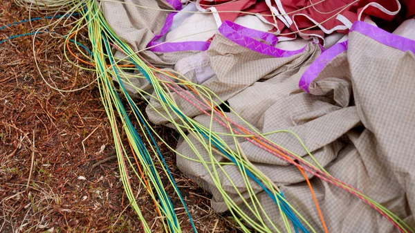 Primer plano de correas, paracaídas y mochila acostados en el campo de hierba después de que el submarinista del cielo aterrizara en el campo. Concepto de deporte extremo y afición a la adrenalina — Foto de Stock