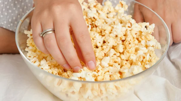 CLoseup av kvinnliga handen tar popcorn från stora glas medan du tittar på film hemma — Stockfoto