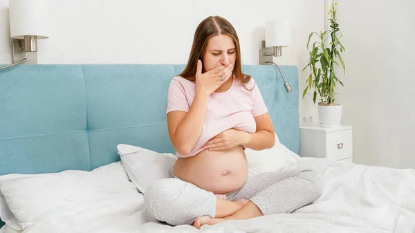 Mulher grávida sentindo-se doente com nausesa sentado na cama de manhã. Intoxicação durante a gravidez — Fotografia de Stock