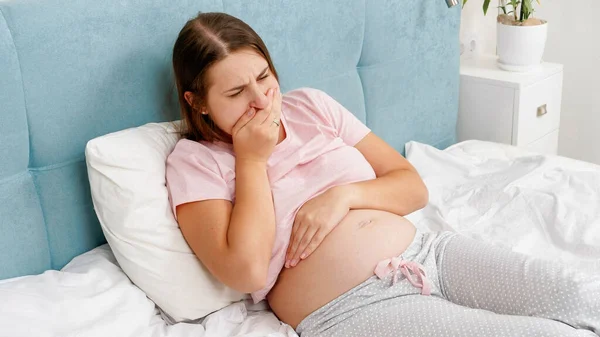 Yougn mujer embarazada despierta por la mañana sintiéndose mal sufriendo de náuseas. Intoxicación durante el embarazo —  Fotos de Stock