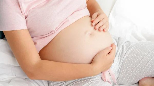 Bela mulher grávida de pijama deitada na cama e acariciando sua barriga. Conceito de paternidade e antecipação feliz do futuro bebê. — Fotografia de Stock