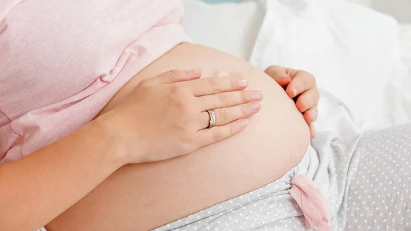 Genç hamile bir kadının karnını okşayıp nazikçe dokunuşunun en üst görüntüsü. Ebeveynlik kavramı ve gelecekteki bebeğin mutlu beklentisi.. — Stok fotoğraf