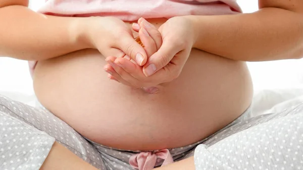 Close-up van jonge zwangere vrouw met een dikke buik die vitaminepillen op handen heeft. Begrip zwangerschap gezondheidszorg en vrouwelijke medische benodigdheden — Stockfoto