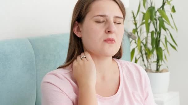 Porträt einer jungen brünetten Frau, die ihren schmerzenden Nacken massiert, nachdem sie Schmerzen gespürt hat — Stockvideo