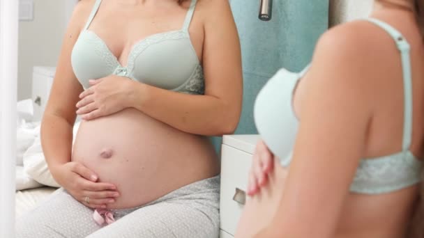 Mulher grávida bonita em sutiã com barriga grande sentado no espelho e olhando em reflexão sobre sua barriga. Bela gravidez e antecipação do bebê. — Vídeo de Stock