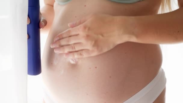 Primo piano di giovane donna incinta con pancia grande utilizzando lozione o crema per ridurre le smagliature sulla pelle. Concetto di bellezza, gravidanza e salute. — Video Stock