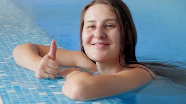 Portret wesołej uśmiechniętej kobiety relaksującej się w basenie i pokazującej kciuki do góry. Szczęśliwi ludzie na wakacjach lub wakacjach — Wideo stockowe