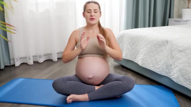 Ritratto di bella donna incinta msiling meditare e fare yoga. Concetto di stile di vita sano, assistenza sanitaria e sport durante la gravidanza — Video Stock