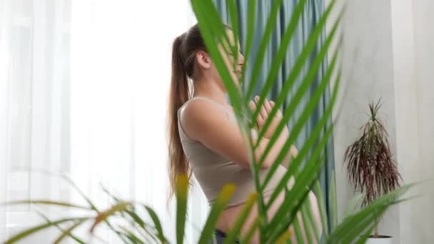 Panning πλάνο της νεαρής εγκύου γυναίκα διαλογισμό και εξάσκηση γιόγκα σε μεγάλο παράθυρο κατά φωτεινό ουρανό. Έννοια του υγιεινού τρόπου ζωής, της υγείας και του αθλητισμού κατά τη διάρκεια της εγκυμοσύνης — Αρχείο Βίντεο