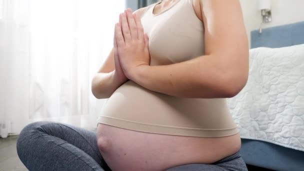 Крупный план беременной женщины, медитирующей и отдыхающей дома на тренажерном коврике. Концепция здорового образа жизни, здравоохранения и спорта во время беременности — стоковое видео