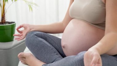 Lotus pozitinde oturup, sabahları yatakta meditasyon yapan hamile bir kadın. Hamilelik boyunca sağlıklı yaşam tarzı, sağlık ve spor kavramı