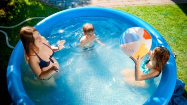 Mutlu mutlu aile, açık havuzda şişme plaj topuyla eğleniyor. Mutlu ve neşeli yaz tatili ve tatil kavramı