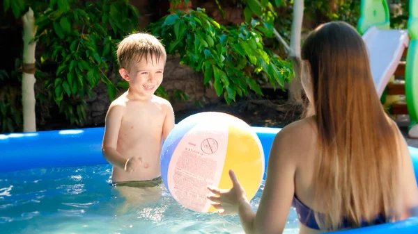 Glücklich lachende Mutter mit kleinem Sohn beim Spielen mit buntem Strandball im Schwimmbad. Sommerurlaub und Urlaub für Familien — Stockfoto