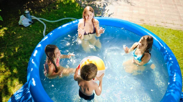 Happy laughing children with mother having fun and playing with inflatable ball in swimming yard. Family summer vacation and holidays — Stock Photo, Image