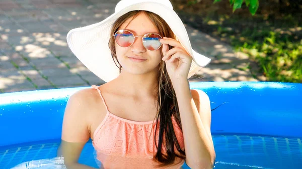 Beautiful girl in sunglasses and hat relaxing in swimming pool — Stock Photo, Image