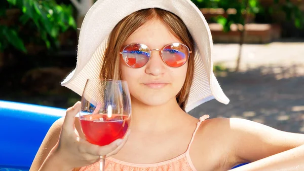 Nahaufnahme Porträt der schönen Teenager-Mädchen mit Hut und Sonnenbrille entspannen im Pool mit leckeren Cocktail. Konzept für glückliche Sommerferien und Urlaub — Stockfoto