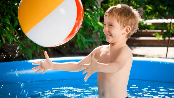 Feliz niño riendo catcing pelota de playa y jugando en la piscina —  Fotos de Stock