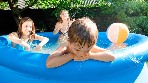 Aile oyun oynarken ve eğlenirken havuz başında oturan üzgün küçük çocuğun portresi. Mutlu ve neşeli yaz tatili ve tatil kavramı — Stok fotoğraf