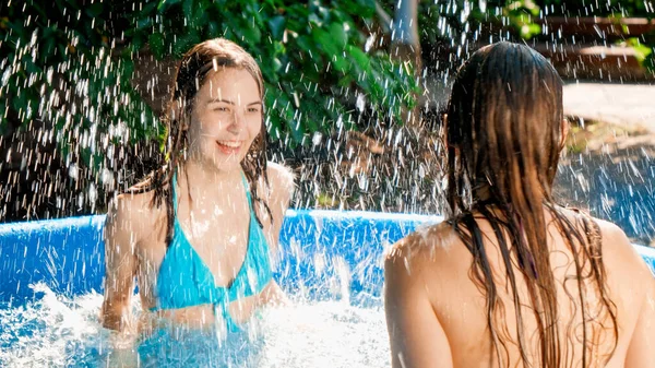 Divertido tiro de adolescente sonriente en traje de baño salpicando agua jugando en la piscina al aire libre. Concepto de felices y alegres vacaciones de verano y vacaciones — Foto de Stock