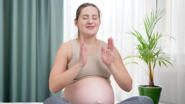 Portrait of smiling pregnant woman practicing yoga folding hands and looking in camera. Concept of healthy lifestyle, healthcare and sports during pregnancy — Stock Video